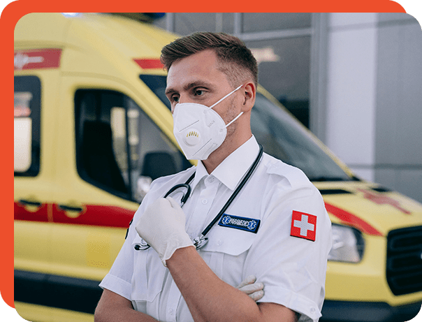 A man in white shirt and face mask standing next to an ambulance.